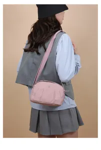 Vue détaillée du sac bandoulière en nylon rose porté par le mannequin, design plissé.