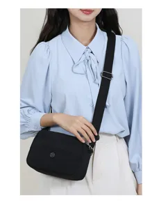 Gedetailleerd overzicht van zwarte nylon crossbodytas met verstelbare riem en voorvakje.