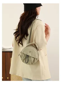 Vue détaillée d'un sac bandoulière rond et chic en nylon kaki clair avec sangle.