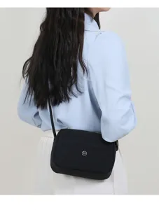 Gedetailleerd overzicht van zwarte nylon crossbodytas voor dames gedragen door model.