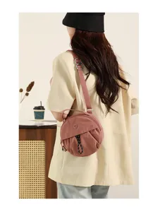 Vue détaillée du sac bandoulière rond et décontracté pour femme, design élégant rose.