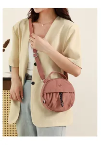 Vue de detail du sac a bandouliere rond et elegant en rose avec ses plis textures.