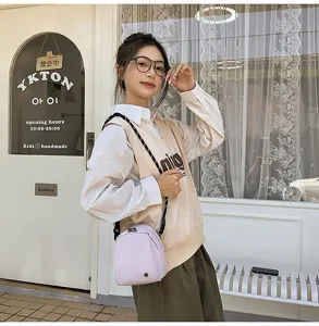Kleine lichte crossbody tas in lichtpaars, casual dagelijkse stijl straatscène detail.