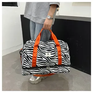 Primer plano de la bolsa de viaje de rayas con asas naranjas y compartimento inferior.