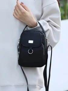 Sac à bandoulière tendance en nylon noir avec plusieurs poches zippées et plaque métallique.