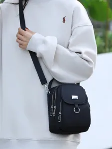 Sac bandoulière en nylon noir pour femme, sac porté épaule minimaliste avec multiples zips.