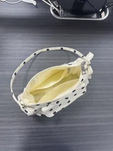 Detailed view of white nylon polka dot underarm hobo bag interior with multiple zipper pockets.