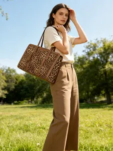 Outdoor detail view of a stylish leopard print tote bag with brown leather and tassel.