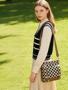 Detailed view of the retro black and white checkered messenger bag worn outdoors naturally.