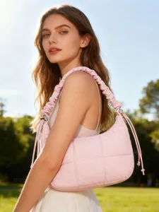 Gros plan d'un sac sous les bras matelassé rose avec bandoulière à volants et cordons réglables.