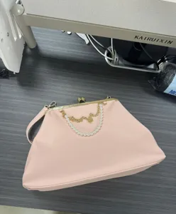 Pink PU leather kisslock handbag detail featuring elegant pearl and gold chain decoration.
