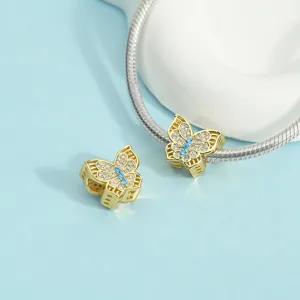 Close-up view of gold butterfly charm with sparkling pavé cubic zirconia and blue center stone.