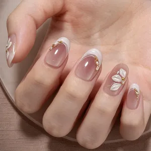 Detailweergave van kunstnagels met nude roze verloop, gesneden bloemen en pareldecoratie.