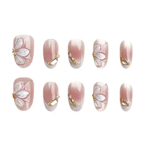 Gedetailleerd uitzicht op nude roze gegradueerde neppe nagels met 3D zilveren bloemen en strass.