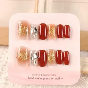 Detalle de uñas postizas hechas a mano con exquisito pan de oro y brillantes pedrerías.