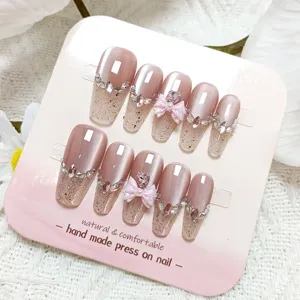 Uñas postizas largas hechas a mano con efecto ojo de gato, brillo, pedrería y lazo rosa.