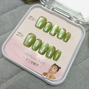 Uñas postizas cortas hechas a mano con efecto ojo de gato verde y purpurina dorada bonitas.