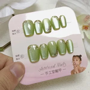 Unas postizas hechas a mano con efecto ojo de gato verde y puntas doradas brillantes.