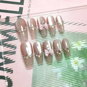 Uñas postizas largas hechas a mano con purpurina ojo de gato pedrería y lazo rosa.