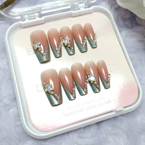 Primer plano detallado de uñas postizas hechas a mano con pedrería y puntas cat-eye.