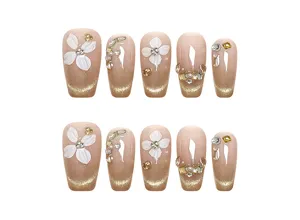 Uñas postizas artesanales con flores blancas 3D, efecto ojo de gato y pedrería brillante.