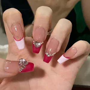 Primer plano detallado de uñas postizas largas con puntas francesas rosas y cristales.
