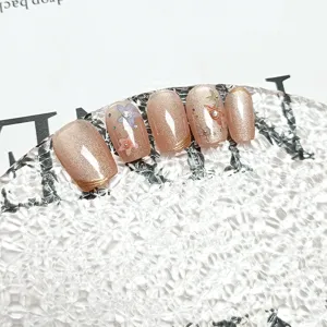 Primer plano detallado de uñas postizas cat-eye hechas a mano con flores y pedrería.