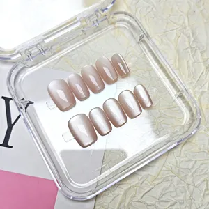 Vista detallada de uñas postizas cortas trapezoidales con efecto ojo de gato en caja transparente.