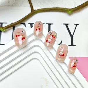 Uñas postizas hechas a mano con motivo de cereza, cristales brillantes y diseño cat-eye rosa.