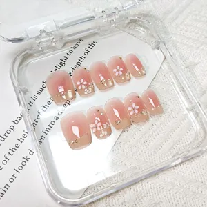 Uñas postizas de ojo de gato 3D con degradado rosa, flores blancas y pedrería fina.