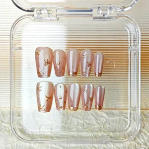 Primer plano detallado de uñas postizas largas con brillo ojo de gato y lazos dorados.