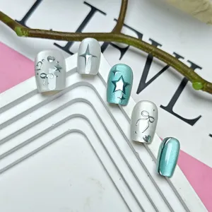 Vista detallada de uñas postizas 3D con estrella brillante, efecto ojo de gato y lazo.