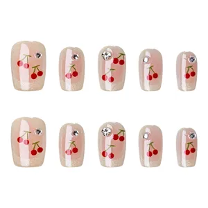 Uñas postizas hechas a mano con bonitos diseños de cerezas y brillantes pedrería fina.