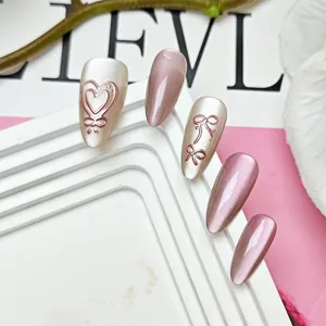 Detail view of handmade almond press-on nails with cat-eye effect, 3D heart and bow designs.