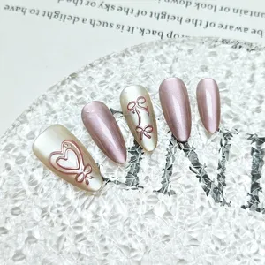 Detailed view of handmade almond press-on nails featuring 3d embossed bows and heart cat-eye.