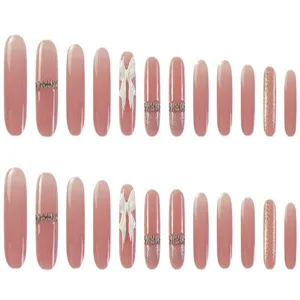 Set di unghie finte sfumate rosa nude con simpatici fiocchi bianchi e dettagli strass.