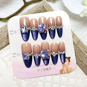Handgemaakte neppe nagels met cat-eye verloop en grote strass stenen voor stijl.