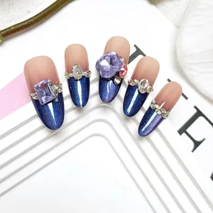 Handgemaakte lange neppe nagels met blauw kattenoog effect en luxe kristallen strass steentjes.