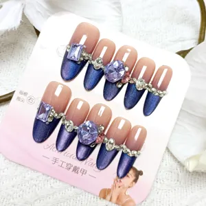 Handgemaakte lange neppe nagels met kattenoog verloop en paarse strass steentjes.