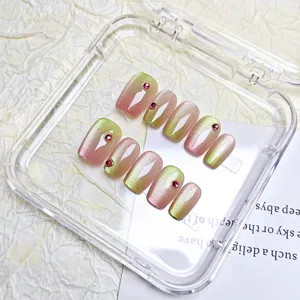 Vue détaillée des faux ongles cat-eye avec dégradé court et accents de strass scintillants.