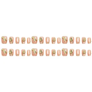 Uñas postizas nude con dijes de mariposa dorados, perlas y pedrería, estilo francés minimalista.