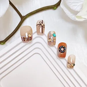 Primer plano detallado de uñas postizas cortas con motivos de cuadros, lazos y bonitos diseños de donas.