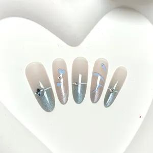 Detalle de uñas postizas cat-eye ovaladas largas con degradado azul y pedrería.