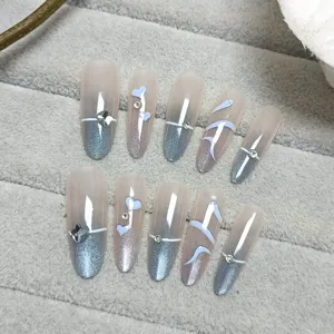 Set de uñas postizas ovaladas largas con degradado azul rosa, gel ojo de gato y pedrería fina.
