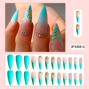 Primer plano de uñas postizas almendradas con degradado azul, líneas doradas y pedrería.