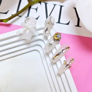 Vista detallada de uñas postizas largas de lujo con pedrería y lazos, diseño elegante.