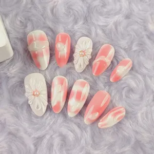 Primer plano de uñas postizas tie-dye rosa con elegantes diseños florales de perlas 3D.