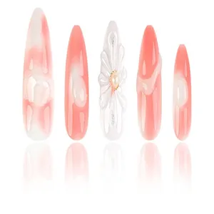 Vista detallada de uñas postizas hechas a mano con degradado rosa y flor de perla 3D.