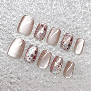 Close up detail of handmade short trapezoid press on nails with cat eye and glitter flakes.