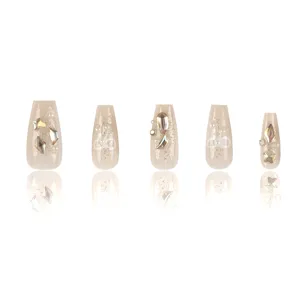 Uñas postizas largas trapezoidales de color champán con purpurina brillante y pedrería